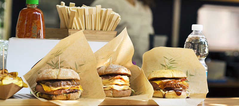 To-go burgers are prominently displayed in a food truck window along with a bottle of water.