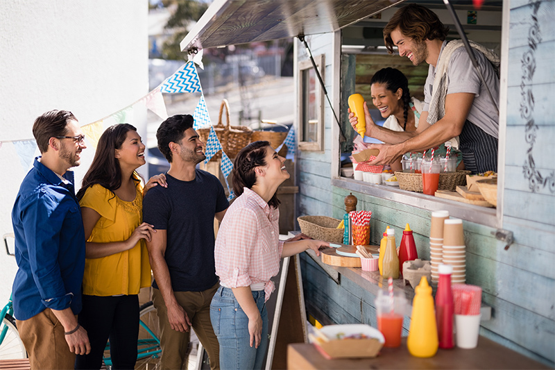 Local residents are being handed food outside a food truck, then guided to the paper products and condiments.